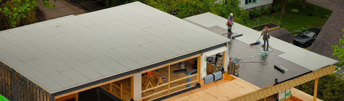 Installation d’une membrane de toit plat sur un bâtiment en construction au Québec.